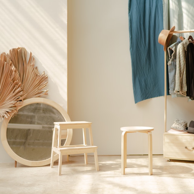 A white wooden barstool and white round white mirror